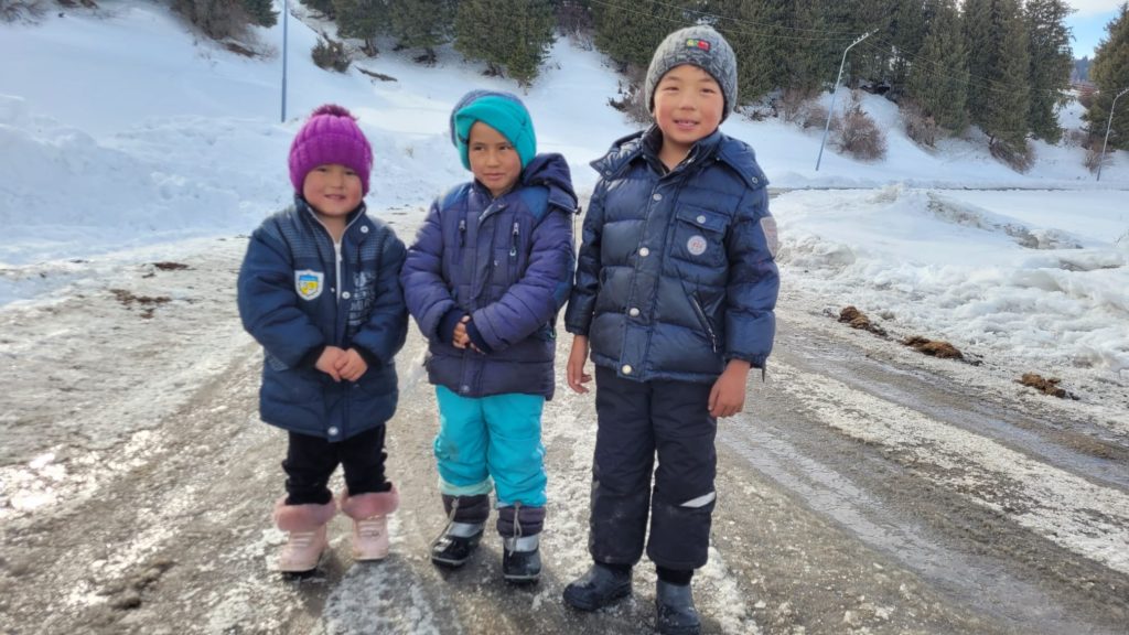 Niños kirguisos en el viaje de e esquí de montaña en Kirguistán