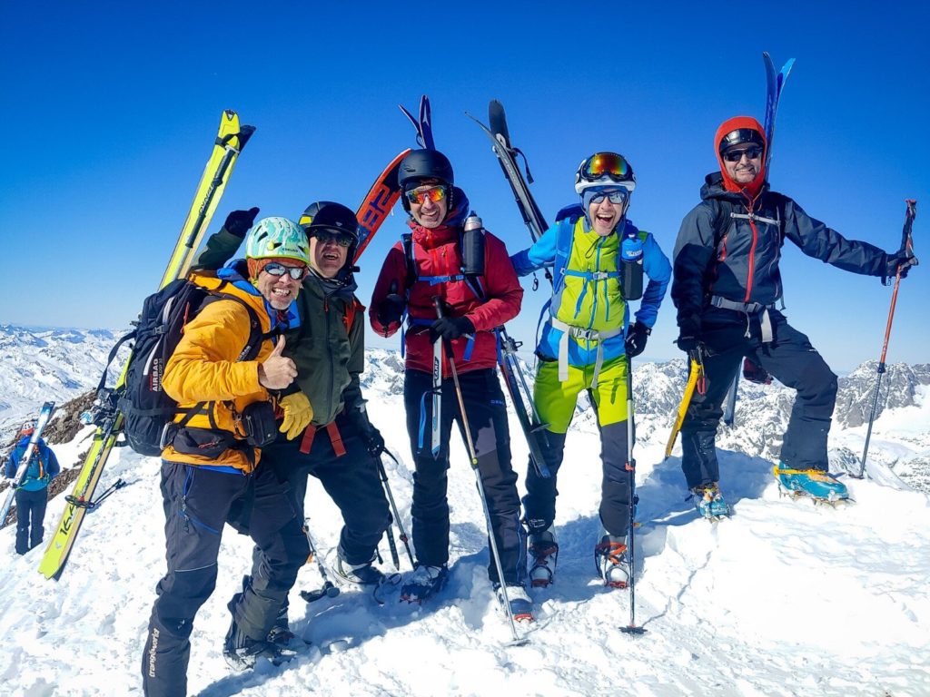 Alegría en la cima de los alumnos y el guía de un curso de esquí de montaña